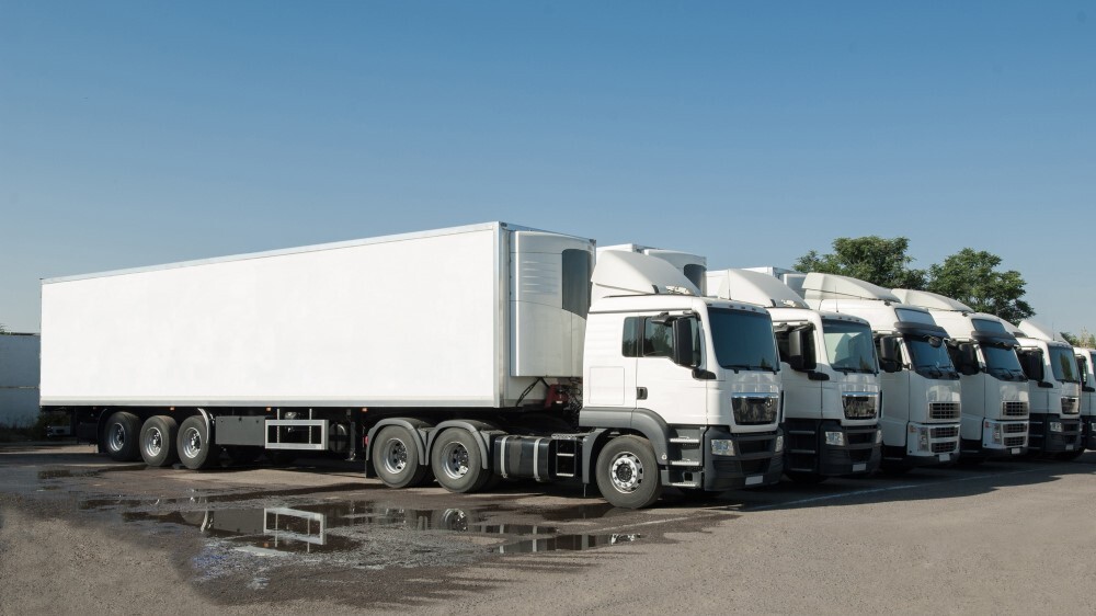 Cargo vehicles stand in a row on a parking. Freight transportation. Truck park