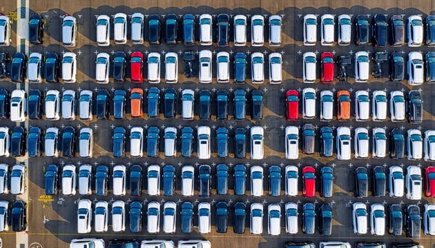 Aerial view of a large parking lot filled with rows of cars, representing vehicle asset tracking, fleet management, and automotive logistics solutions.