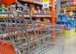Empty shopping cart in a grocery store aisle with shelves of snacks and beverages, representing retail asset tracking and smart inventory management solutions.