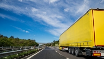 Photo of a yellow truck and trailer on the highway